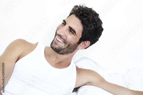 Smiling guy in bed, looking away