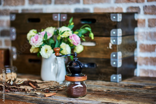 Roasted coffee beans and cinnamon sticks and vintage coffee pot on rustic wooden background.