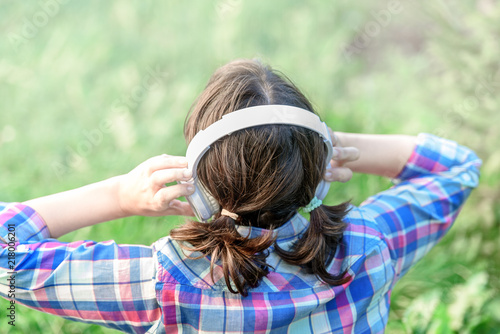 Girl listening to music with headphones in the grassGirl listening to music with headphones in the grass