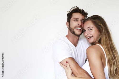 Laughing young couple in white studio, portrait