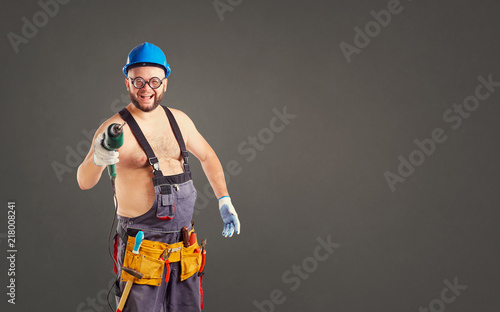 The fat funny man builder with a drill on a background for text. photo
