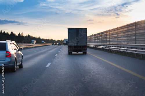 Highway traffic in sunset. road with metal safety barrier or rail. Truck on the asphalt road. Sound acoustic barrier on the right side
