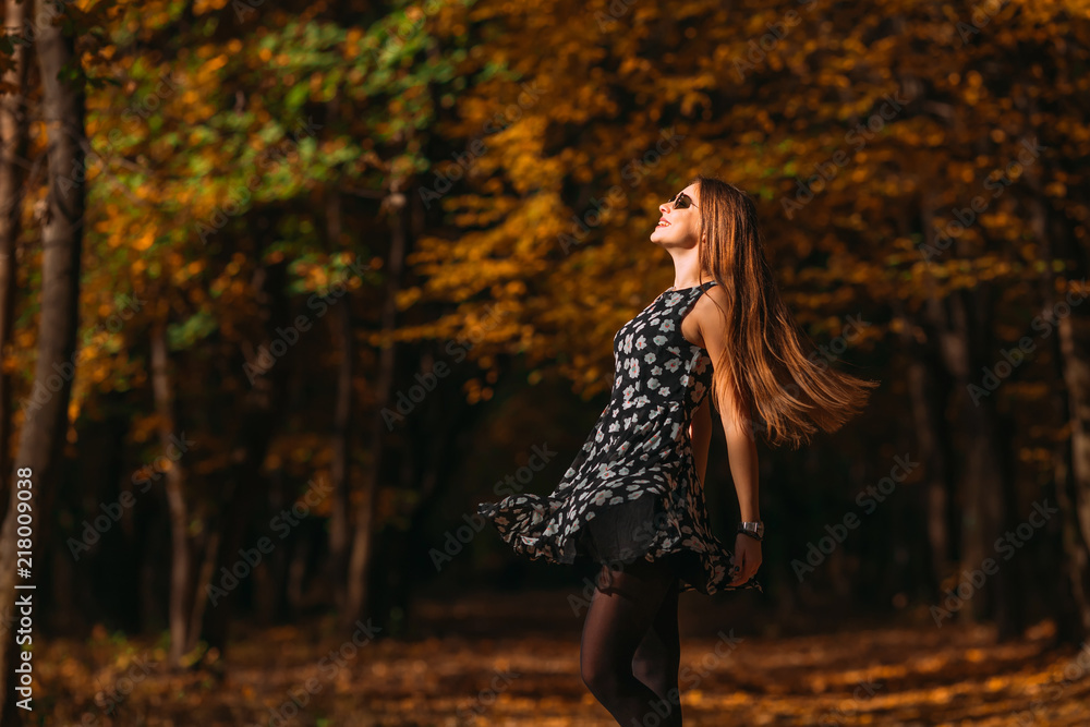 Laughing young girl in a dress in the autumn park dancing and spinning around with flying long hair and smiling at the background of yellow foliage. Walk in the autumn park. Laughing young girl in a dress in the autumn park dancing and spinning around with flying long hair and smiling at the background of yellow foliage. Walk in the autumn park.