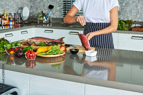 Woman preparing fresh fish in the kitchen..