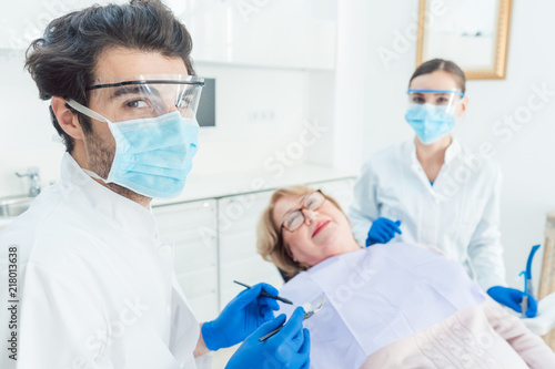 Dentist man in his surgery looking into camera