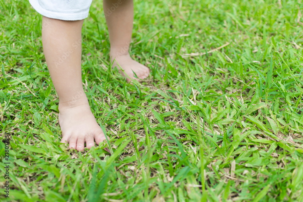 Baby's foot stepping on the grass in the morning with copy space.