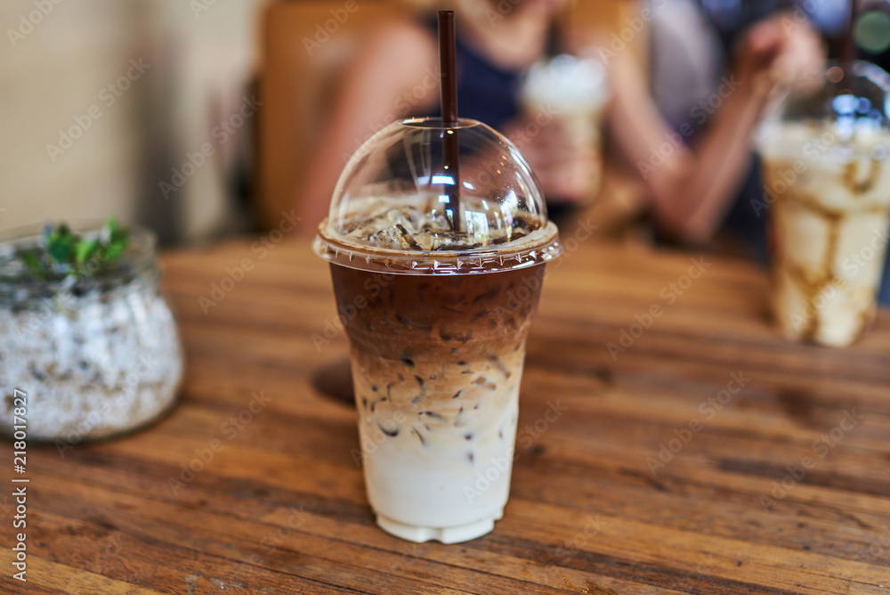 Iced coffee in plastic glass on wooden table background. Iced coffee in plastic glass on wooden table background.