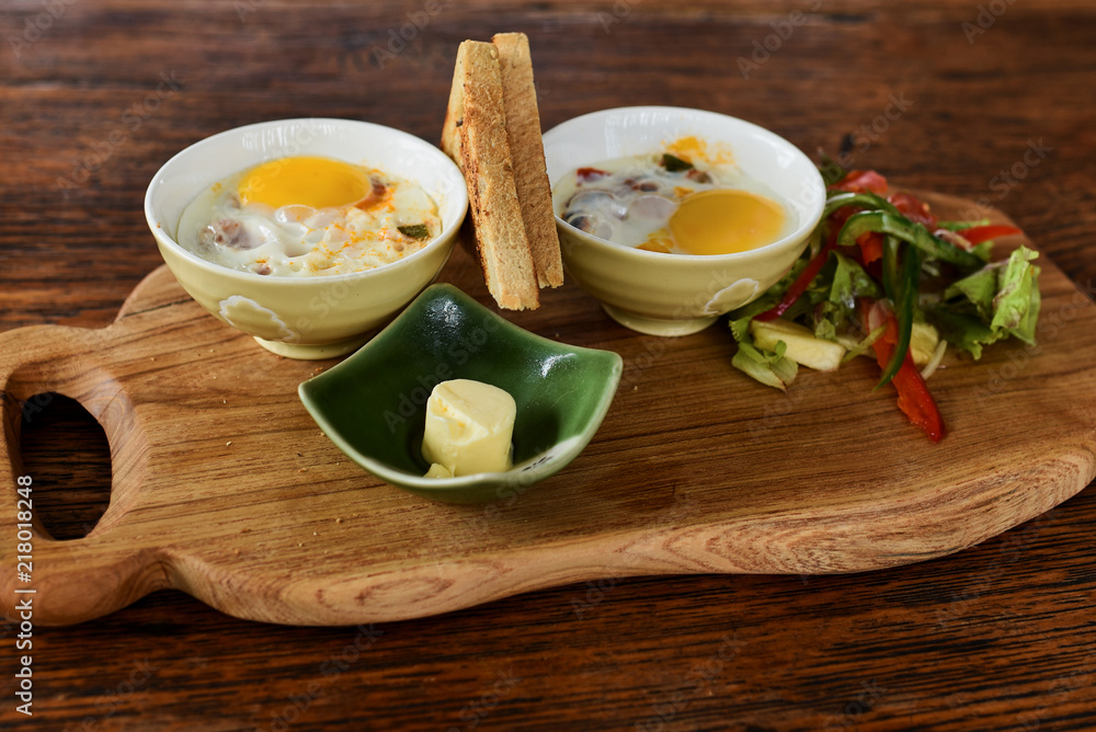 Eggs with butter, chives and vegetables baked in ramekins.