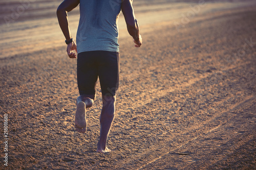 Uomo che corre sulla spiaggia all'alba