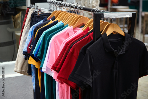 Colorful polo t-shirt for the man on wooden hangers in a retail shop
