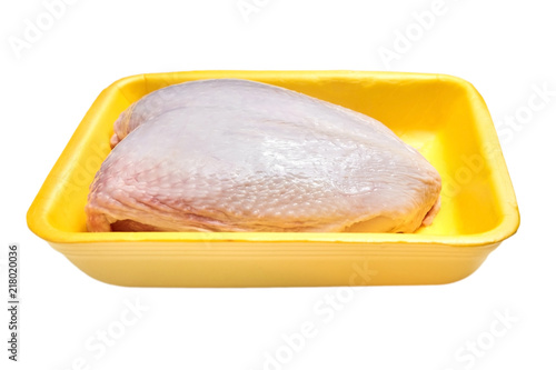 Raw and uncooked chicken breast with skin in a yellow plastic container. Meat of poultry in tray, isolated on white background