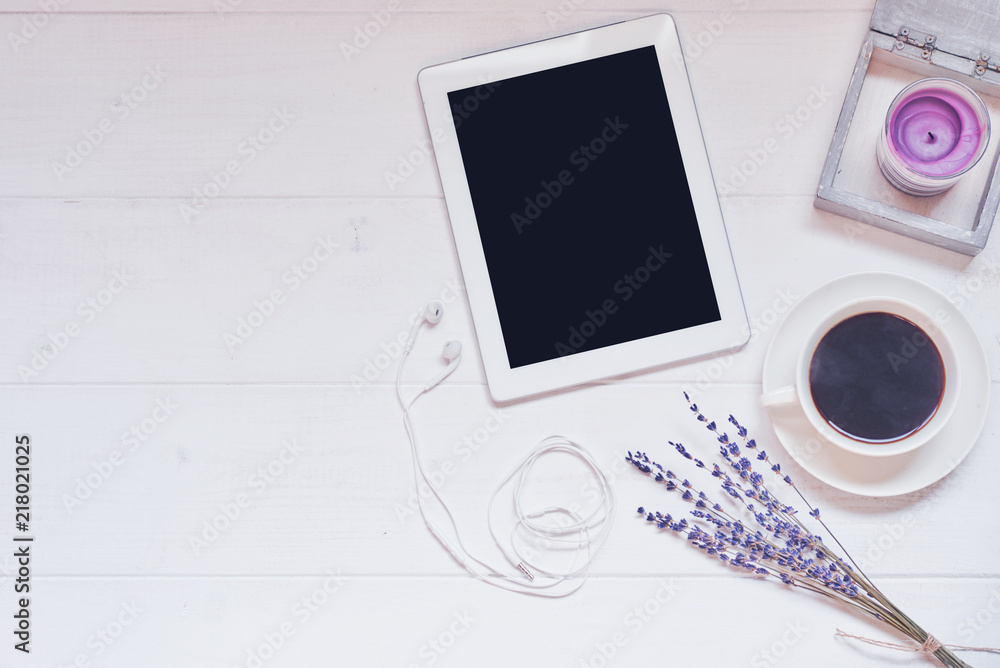 Workspace with cup of black coffee, digital tablet with empty screen, candle, fresh cookie and flowers on white vintage background. Wireless communication concept. Top view, flat lay, copy space. Workspace with cup of black coffee, digital tablet with empty screen, candle, fresh cookie and flowers on white vintage background. Wireless communication concept. Top view, flat lay, copy space.