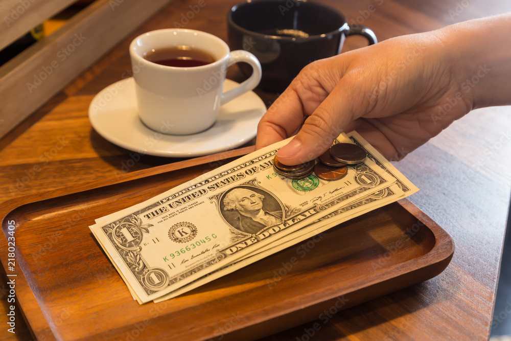 Fotografie Hand putting US money tips in tray.