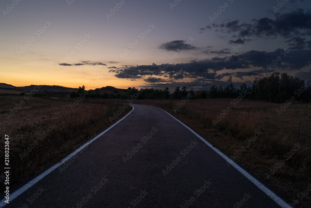 Strada tra i campi al tramonto, Italia