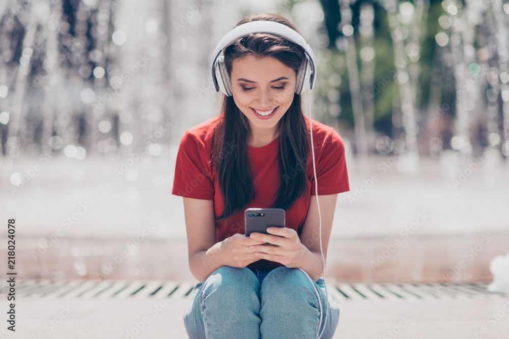 Φωτογραφία Young and nice brunette girl sits near the fountain in headphone