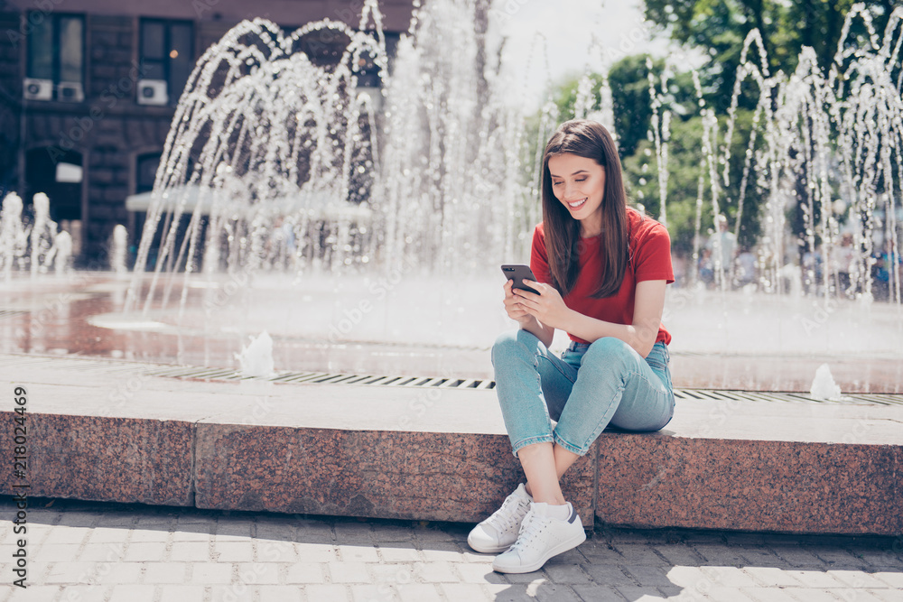 Φωτογραφία Full-size portrait of slim young girl sits near the fountain in