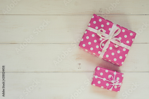 Two pretty pink polka dots gift boxes with white ribbon for Christmas, Valentine, birthday or Mother's Day greeting. Handmade gift boxes on white vintage wooden background. Top view with copy space.
