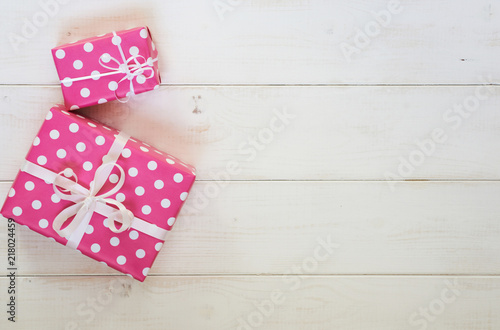 Two pretty pink polka dots gift boxes with white ribbon for Christmas, Valentine, birthday or Mother's Day greeting. Handmade gift boxes on white vintage wooden background. Top view with copy space.