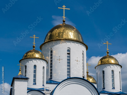 Church with golden domes and crosses on blue sky background. photo