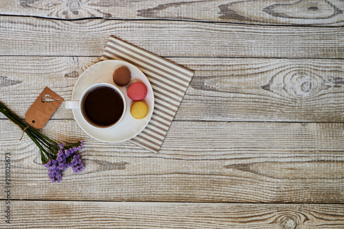 Macaroons on plate with cup of coffee on wooden white background.