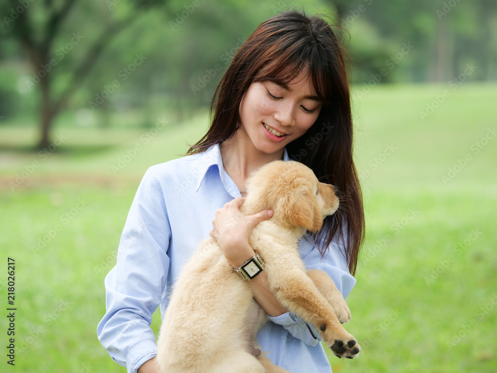 Beautiful young asian woman playing with a cute golden retriever dog in the park. Beautiful young asian woman playing with a cute golden retriever dog in the park.
