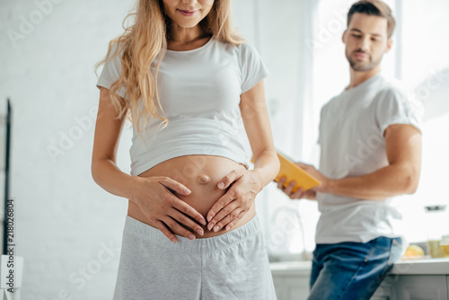 selective focus of man with book in hands looking at pregnant woman at home