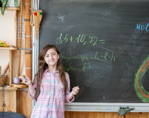 Cute girl schoolgirl near blackboard with chalk photo