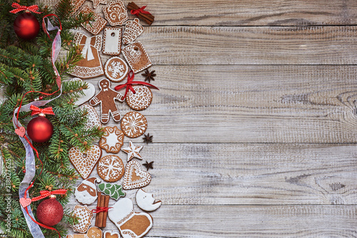 Christmas background with copy space. Traditional gingerbread, christmas tree branch, Christmas spices and red Christmas decor on old white wooden background.