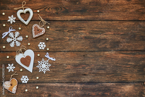 Snowflakes and wooden hearts on the brown wooden table. Christmas background with copy space. Top view.