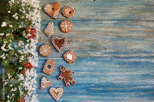 Spicy cookies on the snow-covered wooden background. Christmas border with fir tree branches.