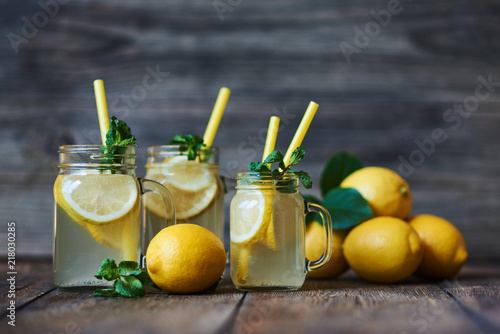 Homemade lemonade with mint and ice. Mason jars lemonade on a rustic wooden background. Delicious and juicy lemonade, full of useful vitamins and antioxidants. Healthy and detox summer drink.
