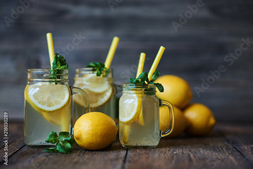 Homemade lemonade with mint and ice. Mason jars lemonade on a rustic wooden background. Delicious and juicy lemonade, full of useful vitamins and antioxidants. Healthy and detox summer drink.