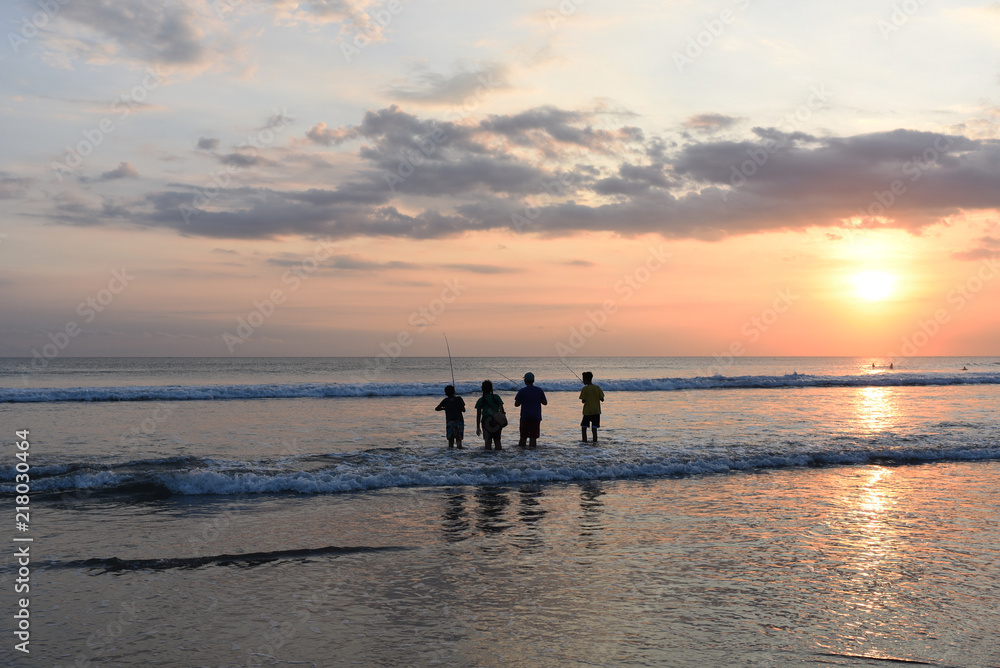 Summer holidays and people concept. Background with black silhouette of children in action fishing at sunrise in the ocean at the early morning. Fishing with rods on ocean landscape of sunrise.. Summer holidays and people concept. Background with black silhouette of children in action fishing at sunrise in the ocean at the early morning. Fishing with rods on ocean landscape of sunrise..