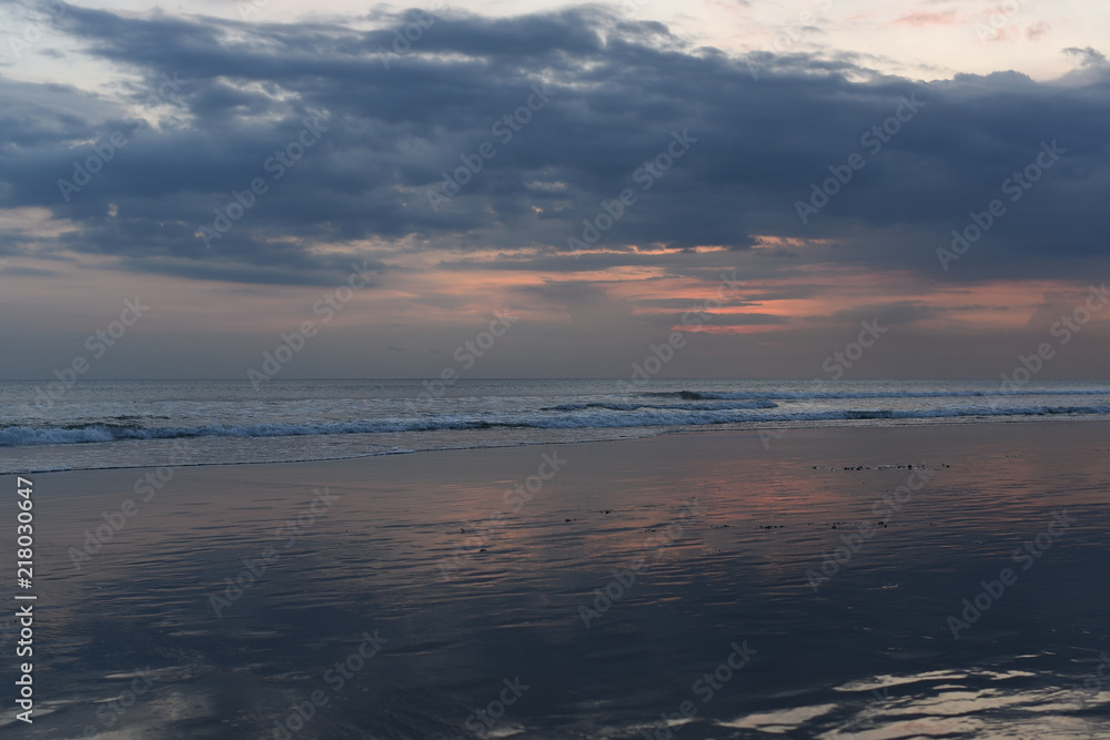 Nature in twilight period. Sunrise or sunset over the sea with tropical beach. Water and sky. Dark tone clouds.