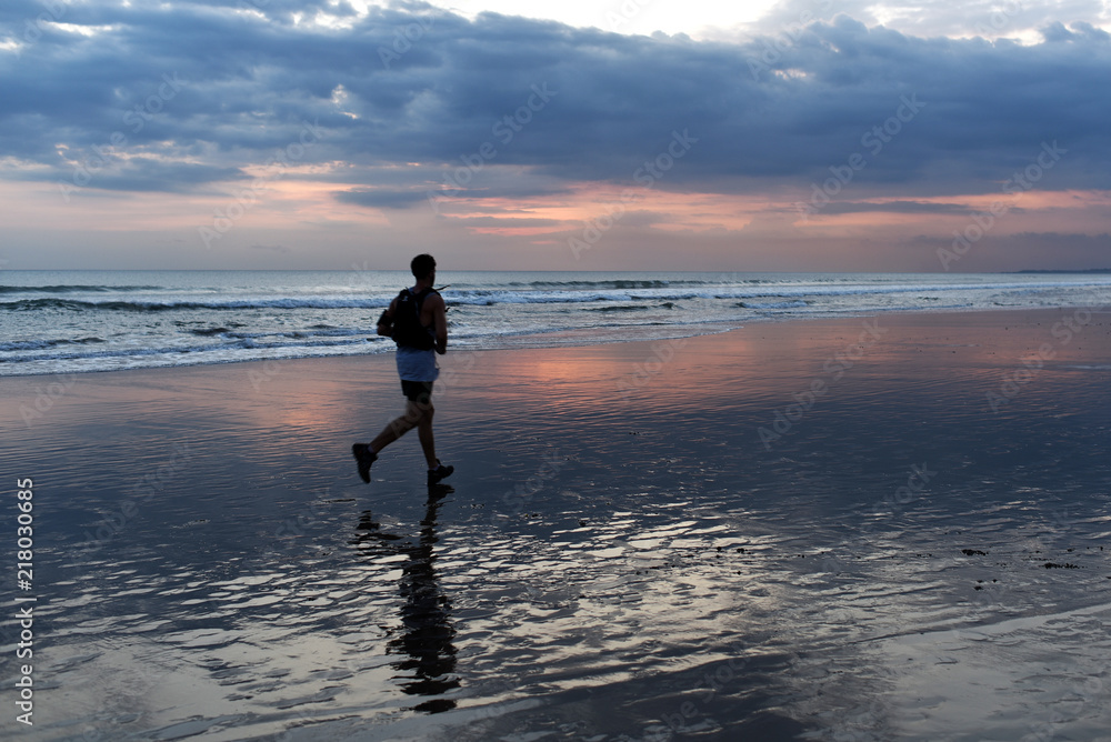 Healthy lifestyle sports. Exercise for cardio training. Silhouette of active athlete running on ocean sandy beach during sunrise shore, purposely motion blur. Beautiful sunrise sky on ocean beach.