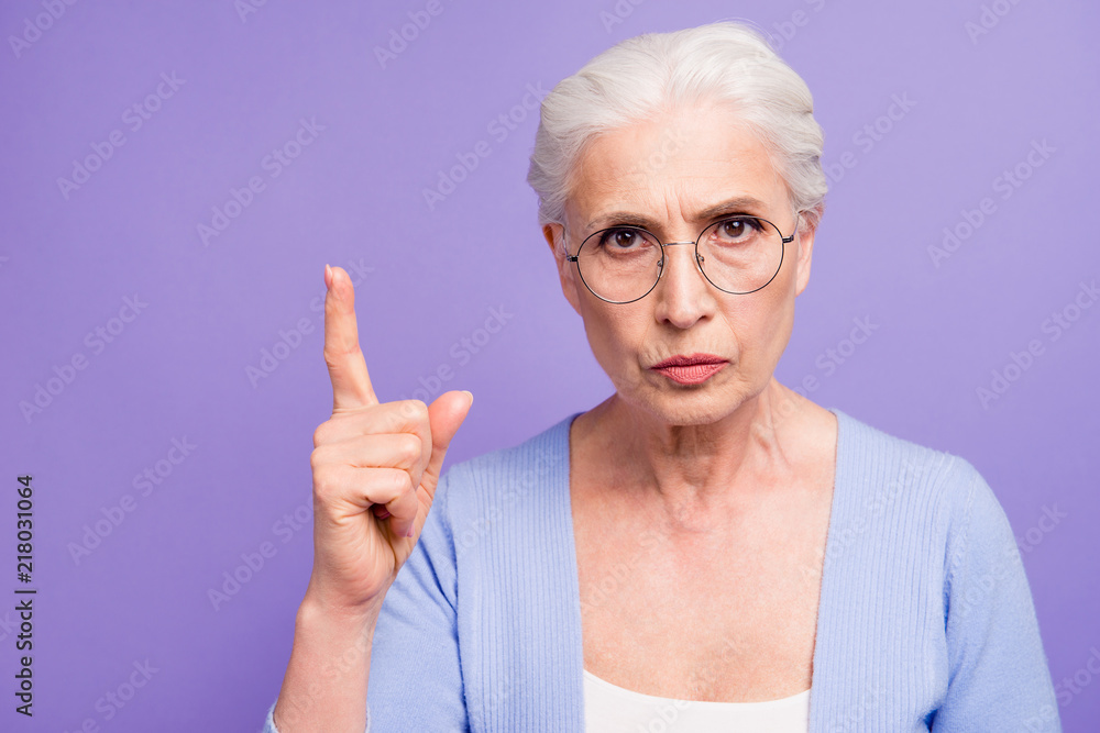 Portrait of grey haired old strict woman wearing glasses pointin Portrait of grey haired old strict woman wearing glasses pointin