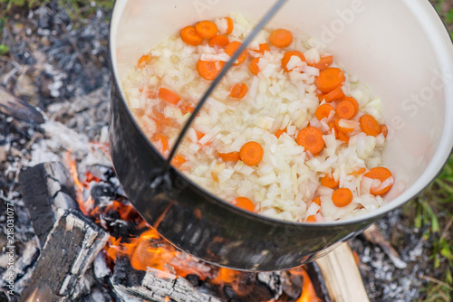 Boiling, hot goulash soup with meat, paprika, potatoes, onion, carrots is the traditional dish of Hungarian cuisine. Meat stew being prepared in crock pot on open fire. Picnic at the weekend in nature