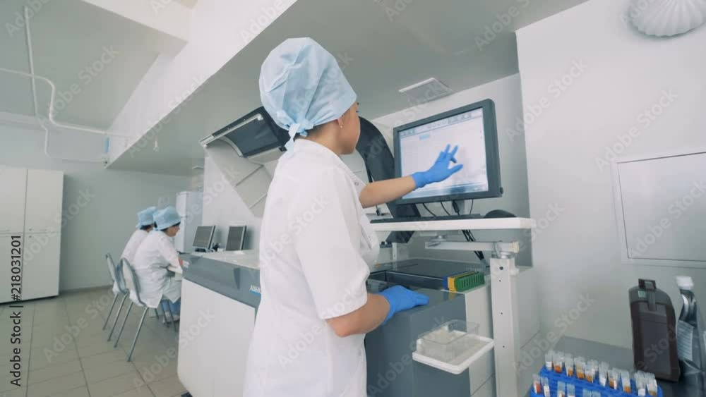 Laboratory facility with a female lab expert working with touchscreen on a Automatic Pharmaceutical Equipment. Laboratory facility with a female lab expert working with touchscreen on a Automatic Pharmaceutical Equipment.