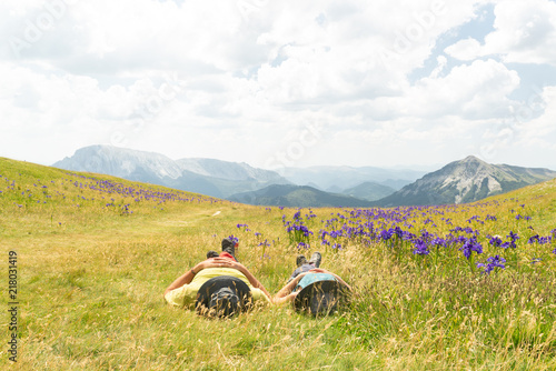  Pareja de excursionistas descansando tumbados en un hermoso prado mientras miran las nubes. Pirineos, España. photo