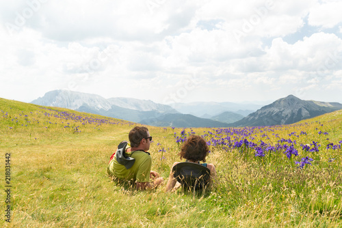 Pareja de montañeros descansando en un hermoso prado mientras miran las montañas. Pirineos, España. photo