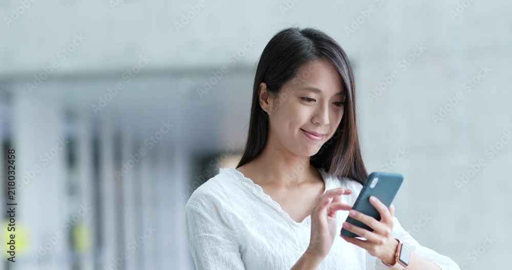 Woman sending sms on cellphone inside building Woman sending sms on cellphone inside building