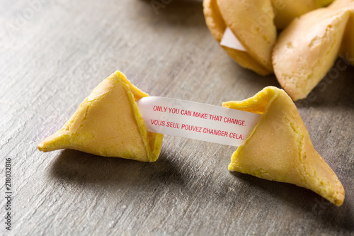 Fortune cookie with message on paper on wooden table