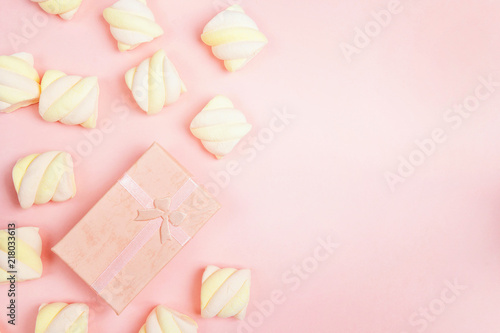 Pink gift box with colorful spiral marshmallows on pink background. Copy space.