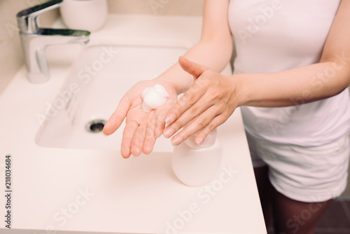 Woman washing up her face with foam cleanser in the morning