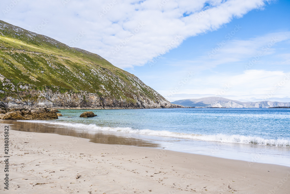 View of the beautiful Keem Bay on Achill Island in Ireland. Sandy beach, calm ocean, tall cliffs and blue skies. Taken in summer. View of the beautiful Keem Bay on Achill Island in Ireland. Sandy beach, calm ocean, tall cliffs and blue skies. Taken in summer.