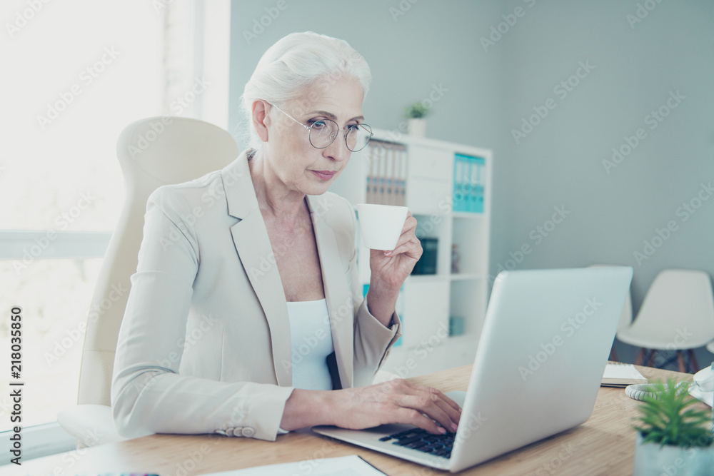 Grey-haired beautiful stylish old serious lady boss typing on co Grey-haired beautiful stylish old serious lady boss typing on co