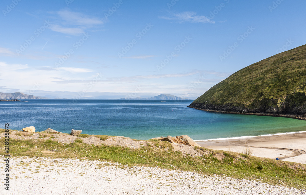 View of the beautiful Keem Bay on Achill Island in Ireland. Sandy beach, calm ocean, tall cliffs and blue skies. Taken in summer.