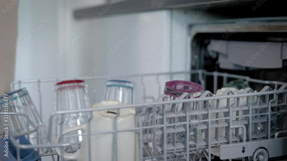 man is taking out a tableware from dishwasher in kitchen after cleaning, close-up of hands, putting it on table man is taking out a tableware from dishwasher in kitchen after cleaning, close-up of hands, putting it on table