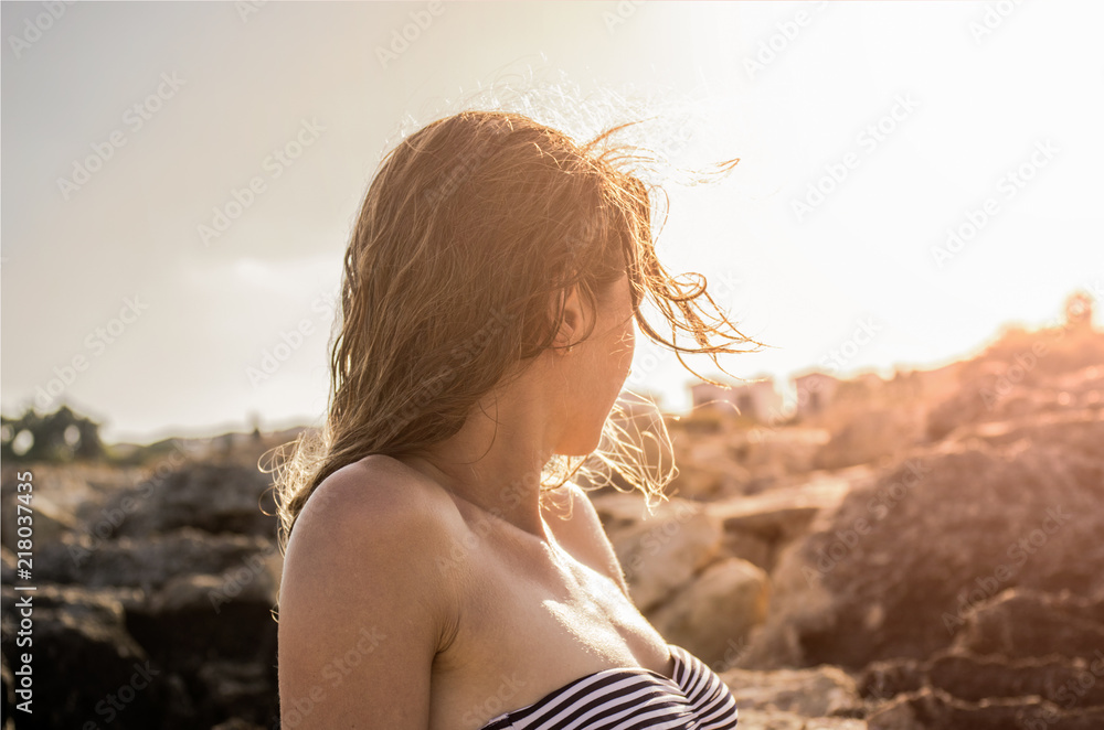 Portrait of sunbathing woman with wet hair looking at sunset