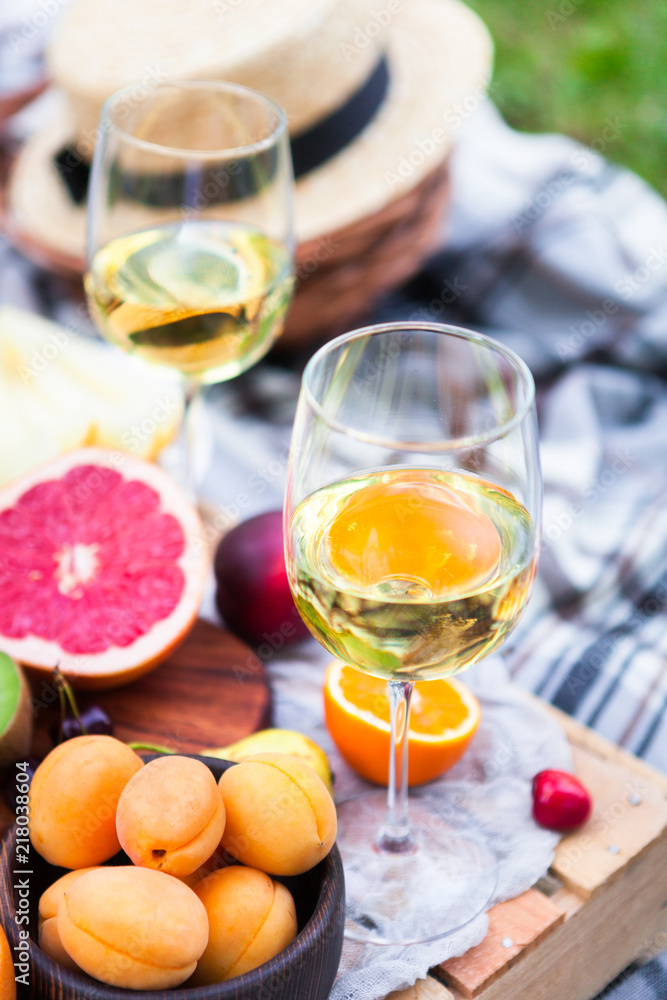 Picnic background with white wine and summer fruits on green grass, summertime party Picnic background with white wine and summer fruits on green grass, summertime party
